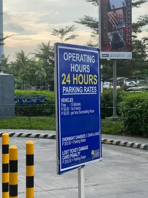 a sign that says operating hours hours parking rates at DMV Trinity Stay in Manila