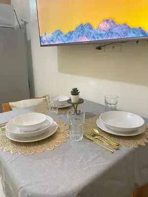 a table with white plates and glasses on it at Casa California by AC Haven in Shore Residences near MOA Pasay City in Manila