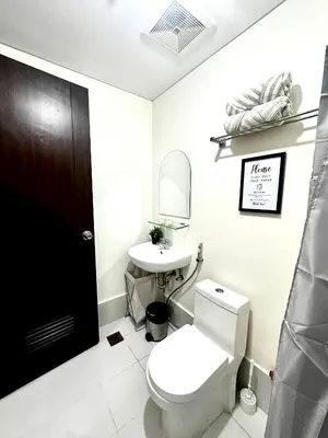 a bathroom with a white toilet and a sink at Candice Empire Garden in Manila