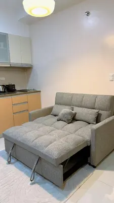 a couch sitting in a room with a kitchen at A Studio Unit in McKinley Near Venice Grand Canal Mall in Manila