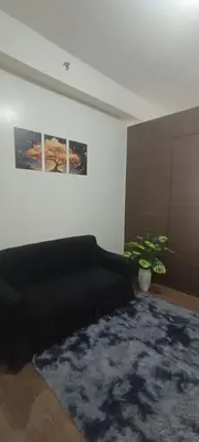 a living room with a black couch and a rug at Hailar Property Management in Manila