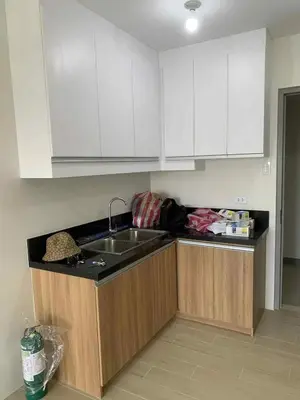 a kitchen with white cabinets and a sink at Cozy oozy apartment in Manila