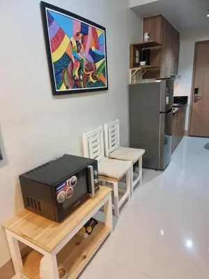 a kitchen with a microwave on a table with chairs at D'Annes Holistay in Manila