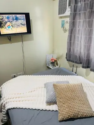 a bedroom with a bed with a tv on the wall at The Cozy Nook in Manila