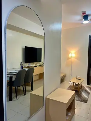 a mirror reflecting a living room with a table and a television at Mandarin Suite Stay in Manila