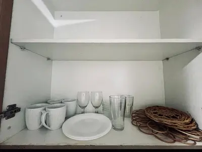 a shelf with wine glasses and plates on it at The Tropical Haven at Shore in Manila