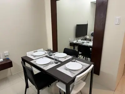 a dining room with a table and chairs and a television at Casa Rosie in Seibu Tower - homey 1BR near BGC High Street in Manila