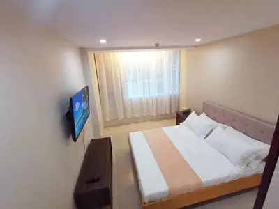 a bedroom with a bed and a tv on a wall at Casa Rosie in Seibu Tower - homey 1BR near BGC High Street in Manila