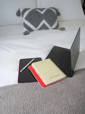 a laptop computer and a book on a bed at Maison Inea in Manila