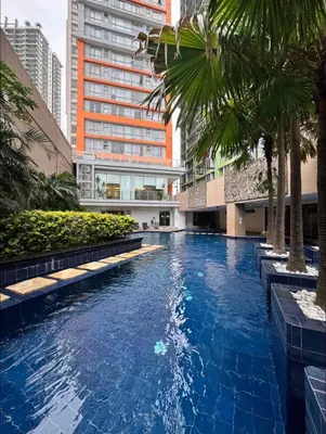 a swimming pool in the middle of a building with palm trees at Spacious 1-BR Condo near BGC w Pool and Gym in Manila