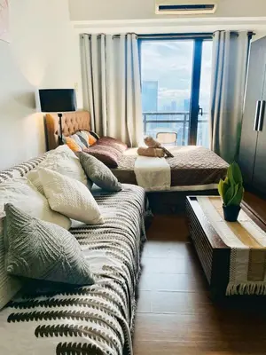 two beds in a room with a large window at Poblacion Makati with Pool, Gym, Jacuzzi, Pool Table and fast wifi in Manila