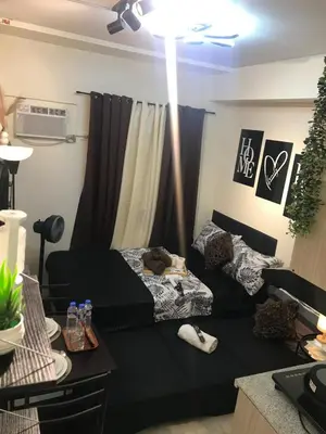a living room with a black couch and a table at InMer's D Staycation in Manila