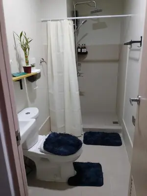 a bathroom with a toilet and a shower with blue rugs at 1 Bedroom Apartment with Mountain View and WiFi in Manila