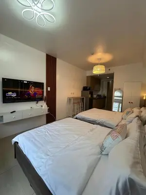 two beds in a room with a flat screen tv at Modern and Cozy home near MOA in Manila