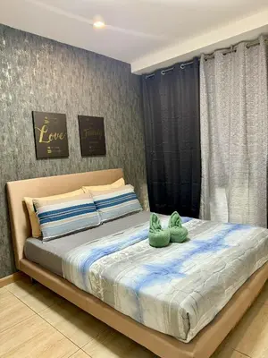 two green stuffed animals sitting on top of a bed at The Gramercy Residences in Manila
