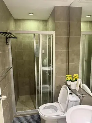 a bathroom with a shower and a toilet and a sink at The Gramercy Residences in Manila