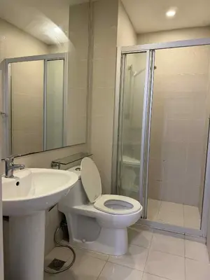 a bathroom with a toilet and a sink and a shower at The Gramercy Residences in Manila