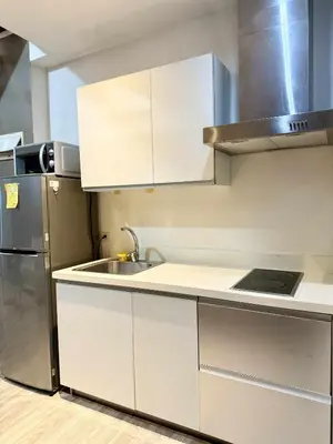 a kitchen with white cabinets and a stainless steel refrigerator at The Gramercy Residences in Manila