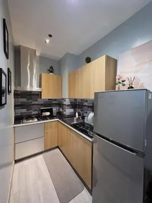a kitchen with a stainless steel refrigerator and wooden cabinets at Stay in Makati 1-BR Condo with Pool, Fast WiFi, Gym, Balcony in Manila
