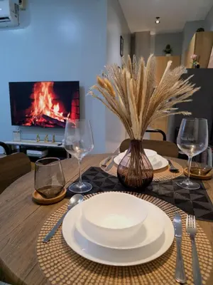 a table with plates and wine glasses and a fireplace at Stay in Makati 1-BR Condo with Pool, Fast WiFi, Gym, Balcony in Manila