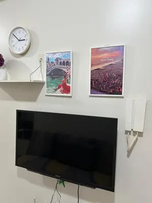 three posters and a clock on a wall with a television at Mall of Asia residence shore 3 in Manila