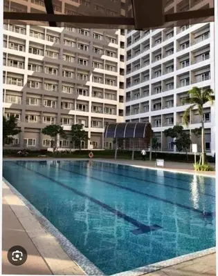 a swimming pool in front of a large building at Room for Rent in Manila
