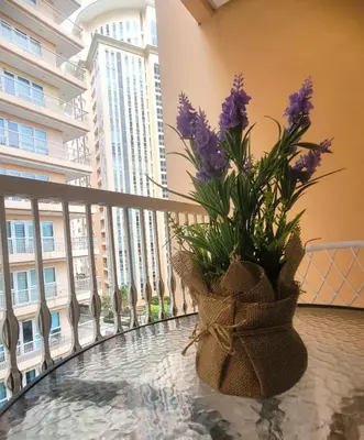 a vase with purple flowers sitting on a balcony at Urban Studio with Balcony in Manila