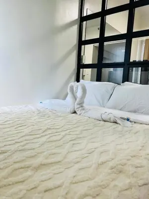 a large bed with a white sheets and pillows at The Sunset Cozy Suite at Shore 1 in Manila