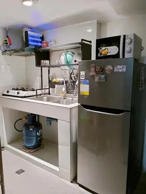 a small kitchen with a sink and a refrigerator at Modern 2 Storey 2BR Home with 2 Parking Space in Manila