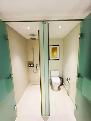 a bathroom with a toilet and a glass door at DE LUX SUITE at Novotel Manila Hotel Residences Acqua in Manila