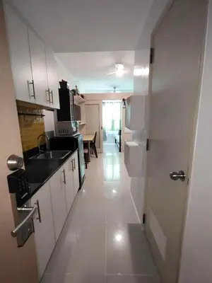 a kitchen with white cabinets and a sink and a table at Lornas Place in Manila