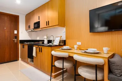 a kitchen with a table with chairs and a television at Brand New Japandi - Modern 1 BR Walk to MOA in Manila