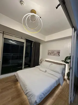 a bedroom with a large white bed and a chandelier at Condo near airport - azure residences in Manila