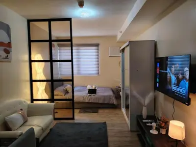 a living room with a bed and a television at NestAway Condo in Manila
