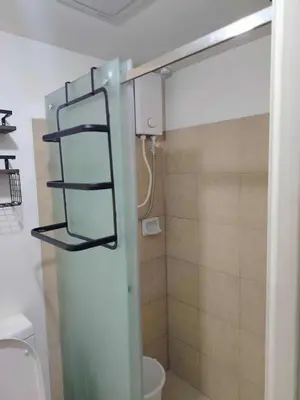 a bathroom with a toilet and a glass shower door at NestAway Condo in Manila