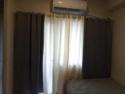 a bedroom with a window with white curtains and a bed at Garcia's Unit02, SMDC Fame Residences in Manila