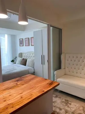 a bedroom with a bed and a table and a couch at penthouse condo in Azure - near airport in Manila