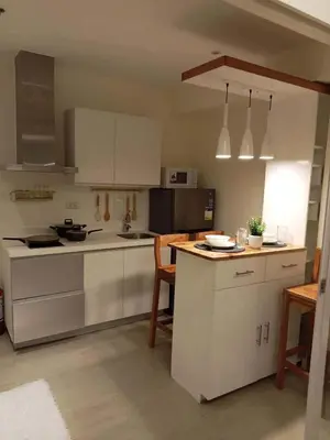 a kitchen with white appliances and a table and chairs at penthouse condo in Azure - near airport in Manila