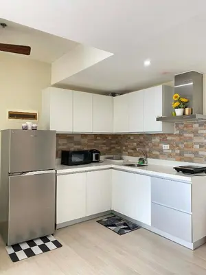 a kitchen with white cabinets and a stainless steel refrigerator at staycation at azure - near airport in Manila
