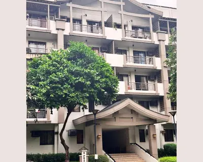 an apartment building with a tree in front of it at Modern 2BR Condo in Acacia Estate, Quiet & Green in Manila