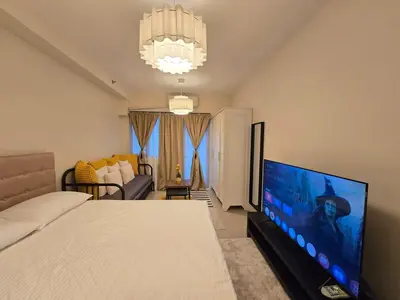 a bedroom with a bed and a flat screen tv at Cozy Modern Studio Near MOA Brand New Furnishings in Manila