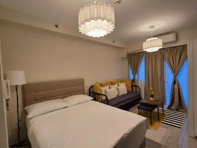 a bedroom with a bed and a couch and chandeliers at Cozy Modern Studio Near MOA Brand New Furnishings in Manila