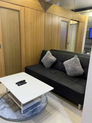 a living room with a black couch and a white table at shell residences -RJ in Manila