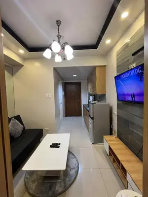a living room with a white table and a tv at shell residences -RJ in Manila