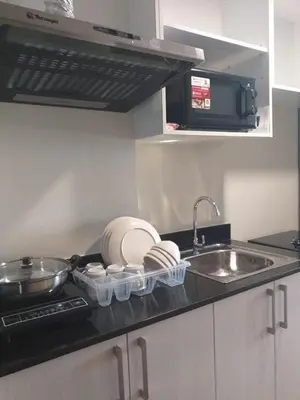 a kitchen counter with dishes and a sink and a sink at MetroStay Studio Legarda in Manila
