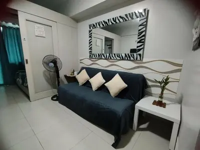 a living room with a blue couch and a mirror at Sea Residences Staycation by Gladys in Manila