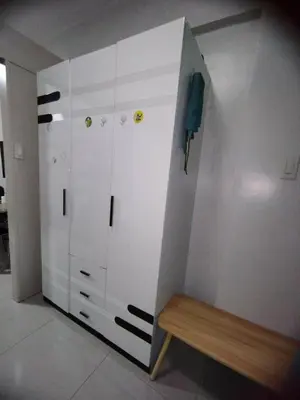 a closet with white cabinets and a wooden bench at Sea Residences Staycation by Gladys in Manila