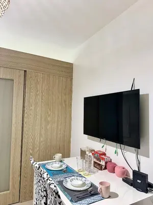 a living room with a table with a tv on the wall at Cozy staycation near Mall of Asia in Manila
