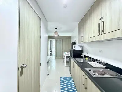a kitchen with wooden cabinets and a sink at Cozy staycation near Mall of Asia in Manila
