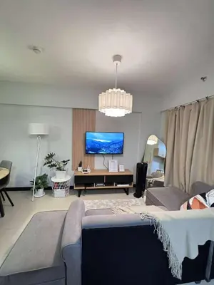 a living room with a couch and a flat screen tv at Alea Residences 1 Bedroom Condo with Pool View Balcony in Manila